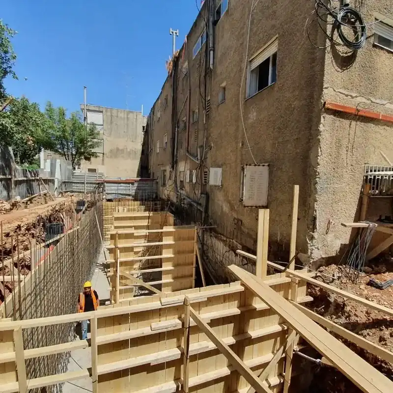 תבניות עץ ורשתות ברזל לקירות מרתף בחפירה צמודה לבניין מגורים ותיק, ברחוב בן זכאי בירושלים
