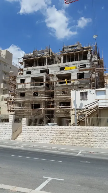 שלד בטון של בניין מגורים עם פיגומים בשלב הביצוע בפרויקט נווה יעקב בירושלים