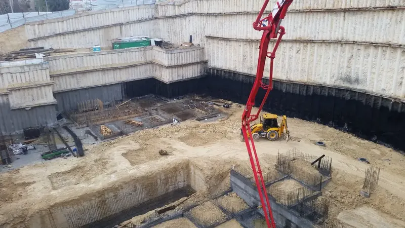 בור חניון עמוק ברמת שרת עם קירות דיפון מעוגנים, משאבת בטון ויסודות בשלבי יציקה