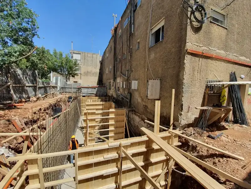 תבניות עץ ורשתות ברזל לקירות המרתף בחפירה צמודה לבניין מגורים ותיק, בפרויקט תוספת בנייה ברחוב בן זכאי בירושלים